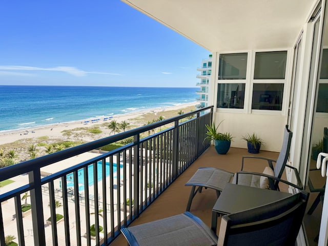 balcony with a water view and a view of the beach