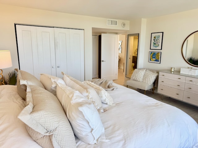 bedroom with a closet, wood finished floors, and visible vents