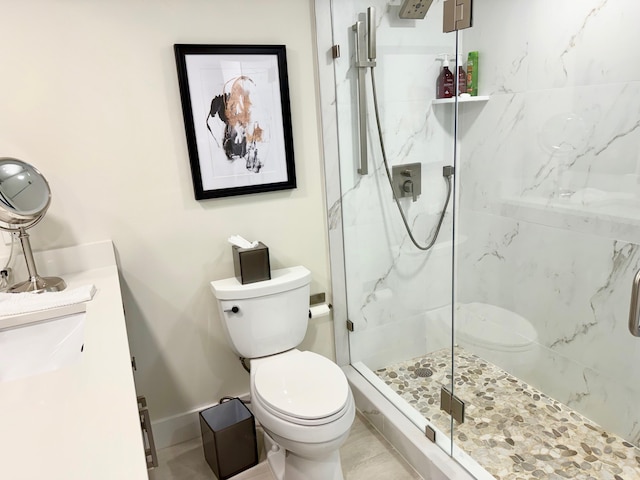 bathroom with baseboards, toilet, vanity, and a marble finish shower