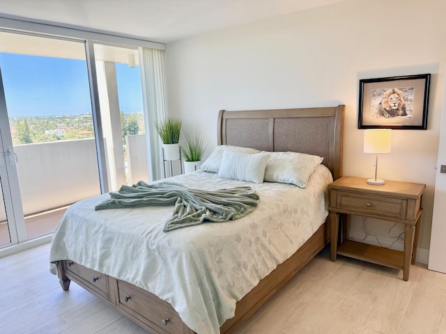 bedroom featuring floor to ceiling windows, light wood-style floors, and access to exterior