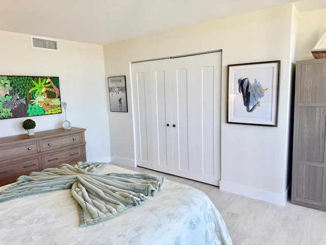 bedroom featuring a closet, visible vents, baseboards, and wood finished floors