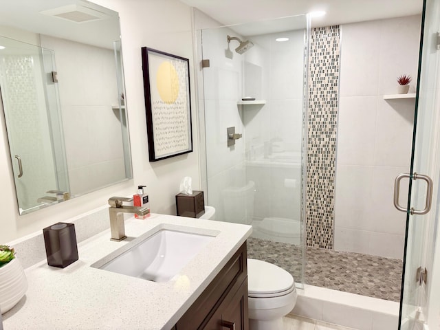 bathroom with a shower stall, toilet, and vanity