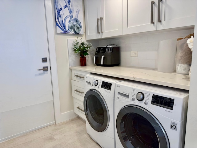 laundry room featuring cabinet space, light wood-style flooring, and washer and dryer