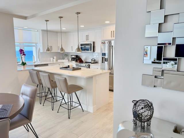 kitchen with light wood-style flooring, a center island, stainless steel appliances, a kitchen bar, and backsplash