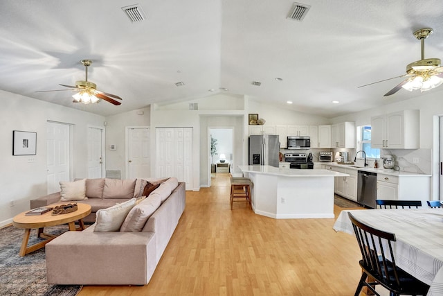 living area featuring visible vents, light wood-type flooring, and ceiling fan