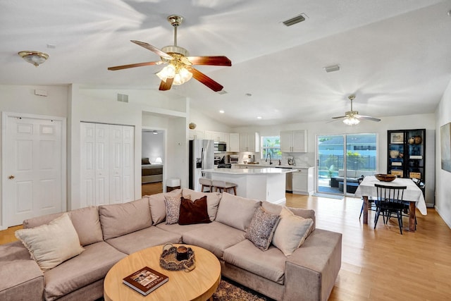 living room with visible vents, light wood-type flooring, ceiling fan, and vaulted ceiling