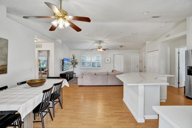 kitchen featuring visible vents, lofted ceiling, a kitchen island, and light wood finished floors