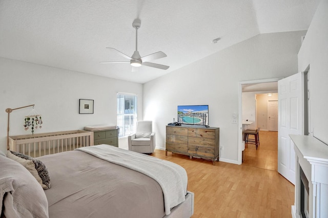 bedroom featuring a textured ceiling, light wood-style floors, baseboards, ceiling fan, and vaulted ceiling