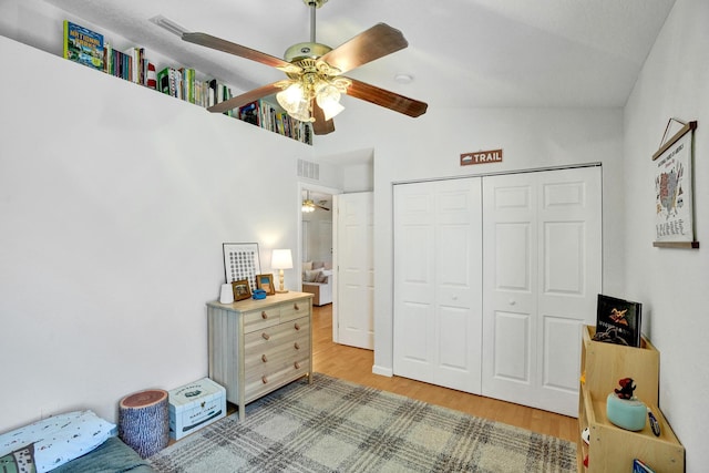 bedroom with visible vents, lofted ceiling, light wood-style floors, a closet, and a ceiling fan