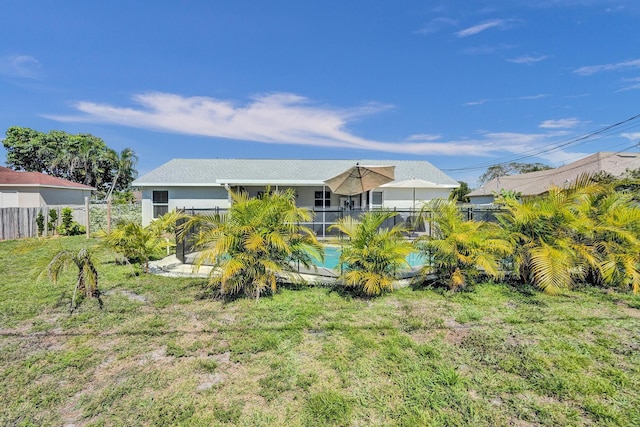 rear view of property featuring a fenced in pool, a lawn, and a fenced backyard