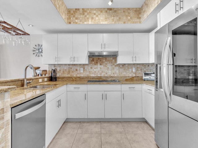 kitchen with under cabinet range hood, a sink, backsplash, stainless steel appliances, and white cabinets