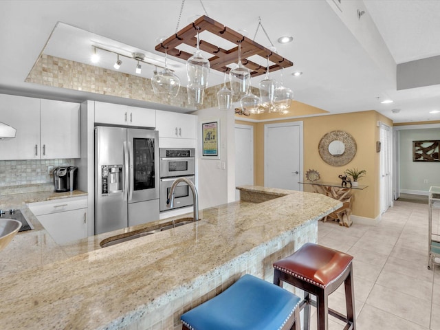 kitchen with decorative backsplash, appliances with stainless steel finishes, light stone countertops, and a sink