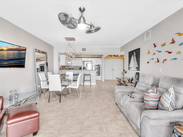 living room featuring light tile patterned flooring, visible vents, and a chandelier