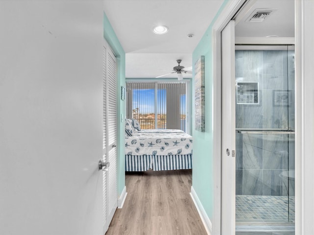 hallway with visible vents, baseboards, and wood finished floors