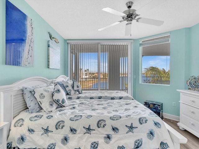 bedroom featuring access to exterior, baseboards, ceiling fan, and wood finished floors