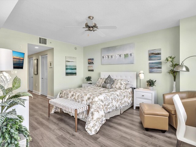 bedroom with visible vents, baseboards, ceiling fan, wood finished floors, and a closet