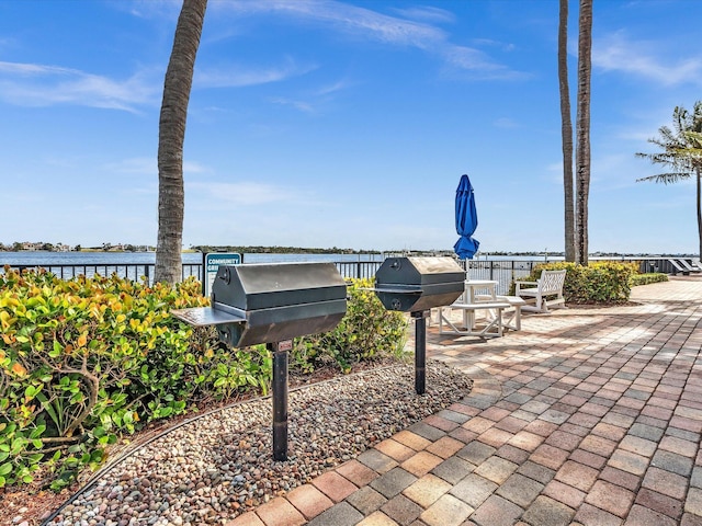 view of community featuring a patio area, fence, and a water view