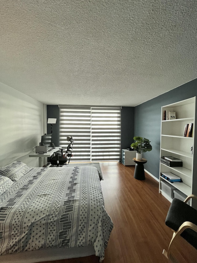 bedroom featuring baseboards, a textured ceiling, and wood finished floors