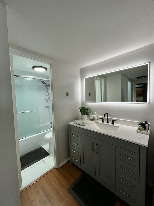 bathroom with shower / tub combination, wood finished floors, vanity, and toilet