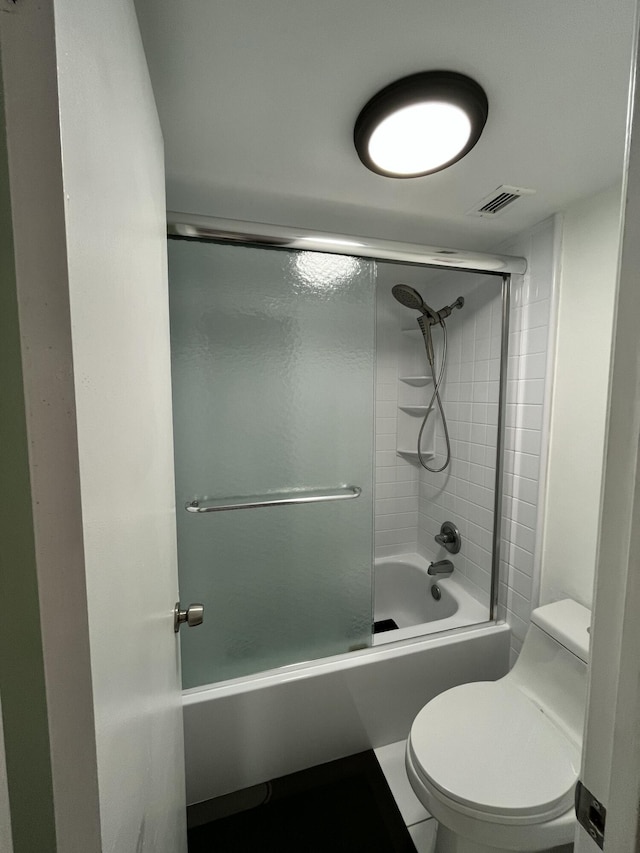 bathroom with visible vents, toilet, and shower / bath combination with glass door