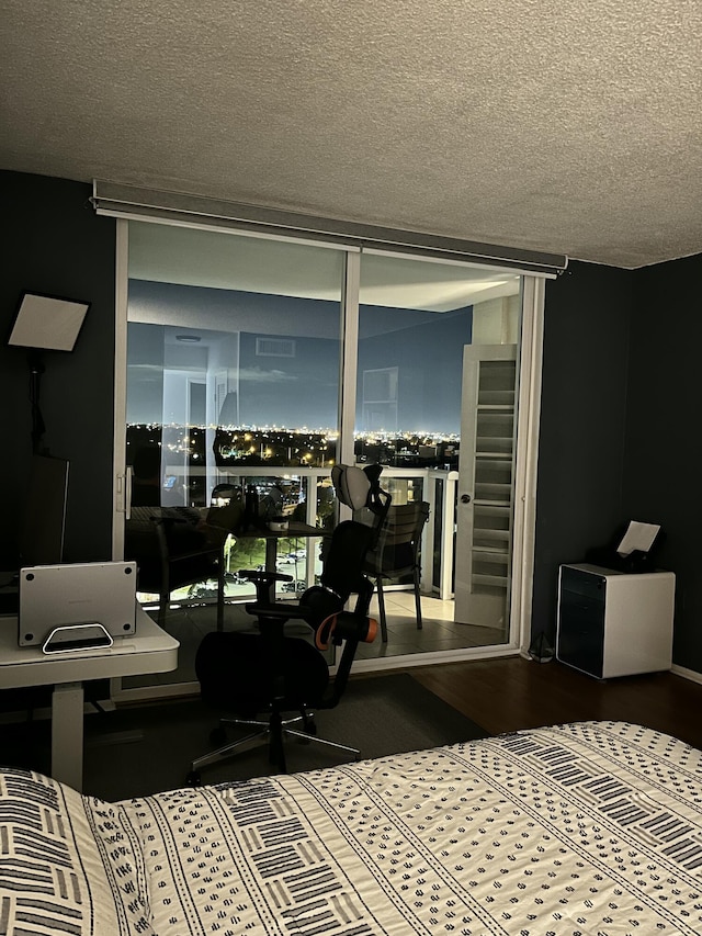 bedroom with floor to ceiling windows, a textured ceiling, and wood finished floors