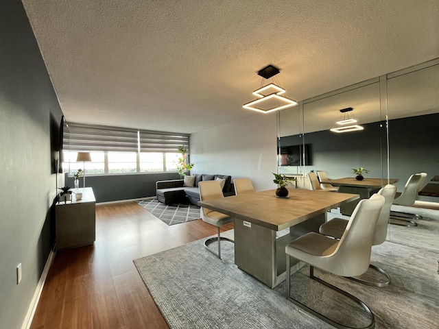 dining room featuring a textured ceiling, baseboards, and wood finished floors