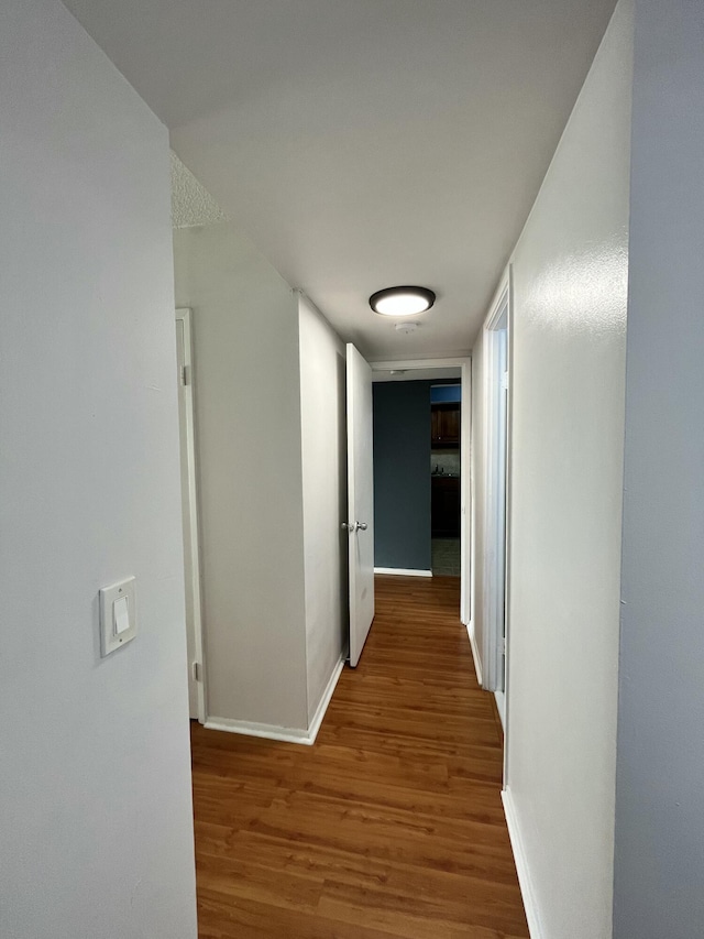 corridor with baseboards and wood finished floors