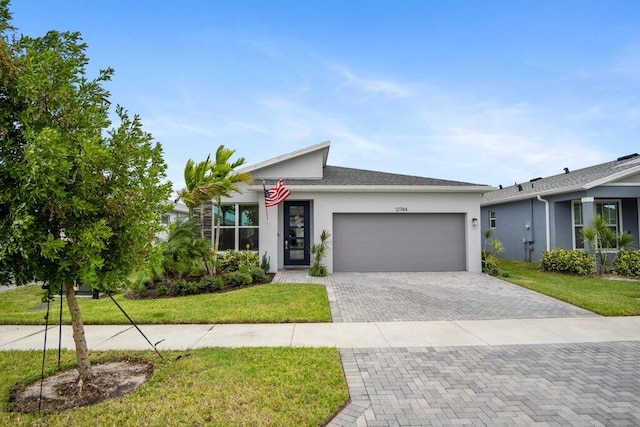 view of front of house with a garage, decorative driveway, a front yard, and stucco siding