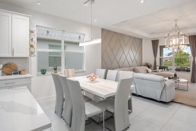 dining room with light tile patterned floors, recessed lighting, a raised ceiling, an accent wall, and a chandelier