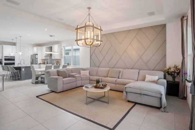 living area with a raised ceiling, an accent wall, light tile patterned flooring, a notable chandelier, and recessed lighting