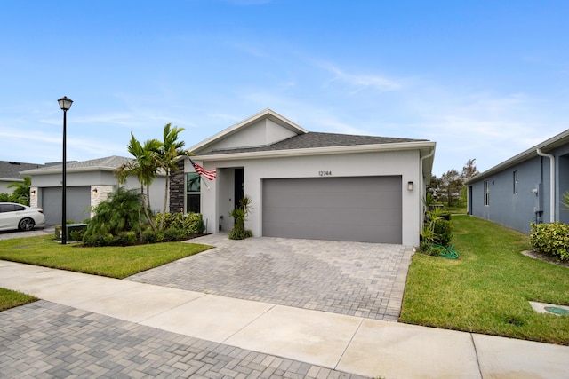 ranch-style house with decorative driveway, stucco siding, a shingled roof, an attached garage, and a front lawn