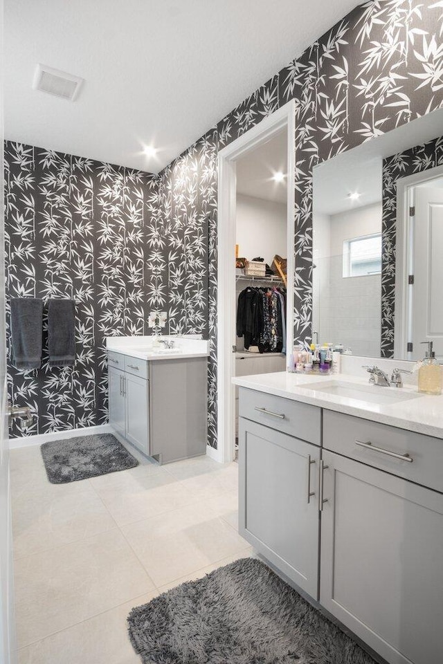 bathroom with tile patterned flooring, two vanities, a sink, and wallpapered walls