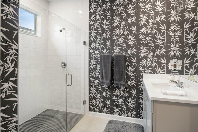 full bathroom with a stall shower, vanity, tile patterned flooring, baseboards, and wallpapered walls