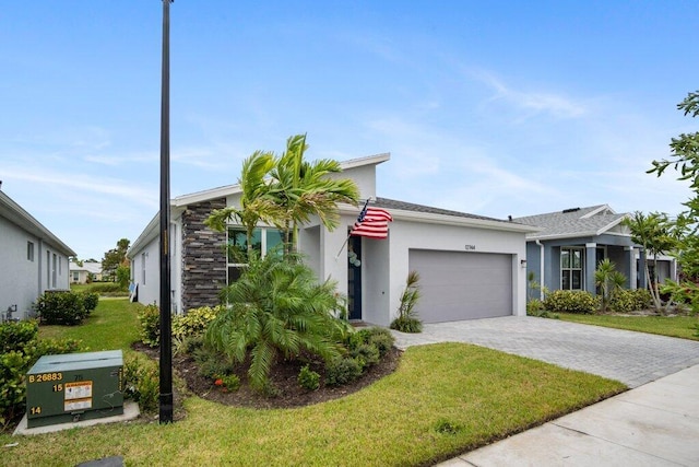 view of front facade featuring a garage, decorative driveway, a front yard, and stucco siding