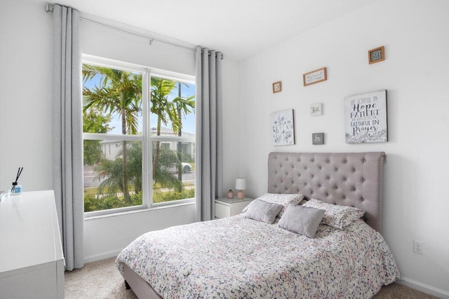 carpeted bedroom featuring multiple windows and baseboards