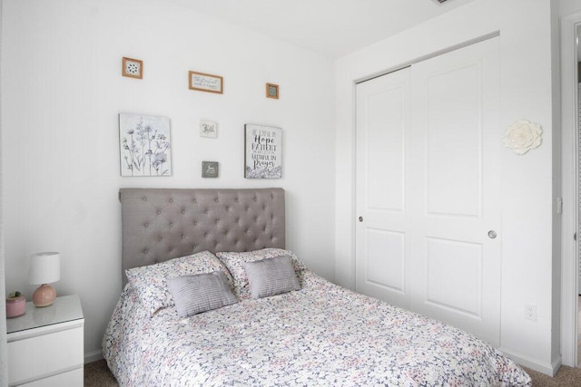 carpeted bedroom with a closet and baseboards