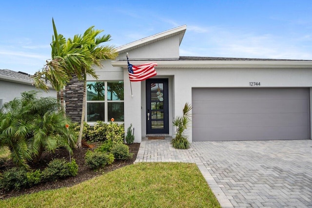 view of front of property with an attached garage, decorative driveway, and stucco siding