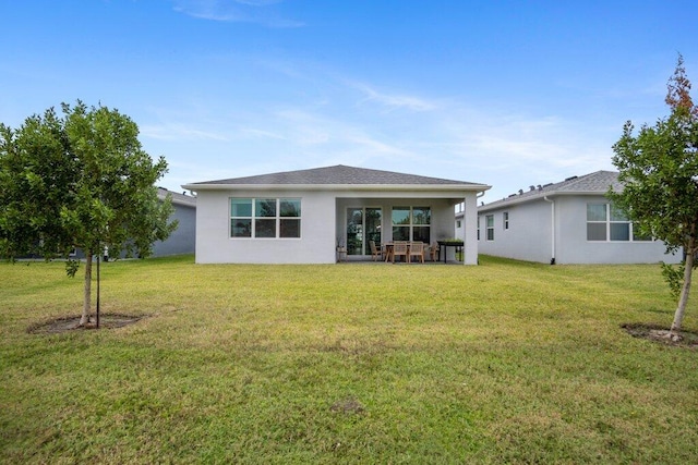 rear view of house with a lawn and stucco siding