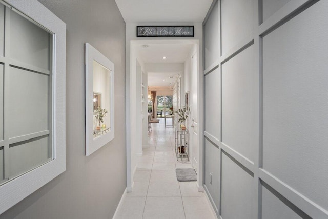 corridor featuring light tile patterned flooring and baseboards