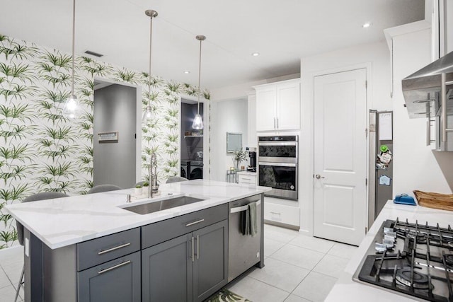 kitchen featuring stainless steel appliances, a sink, white cabinets, and wallpapered walls