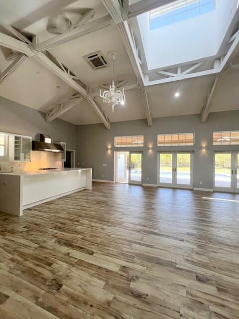 unfurnished living room featuring baseboards, visible vents, wood finished floors, and french doors