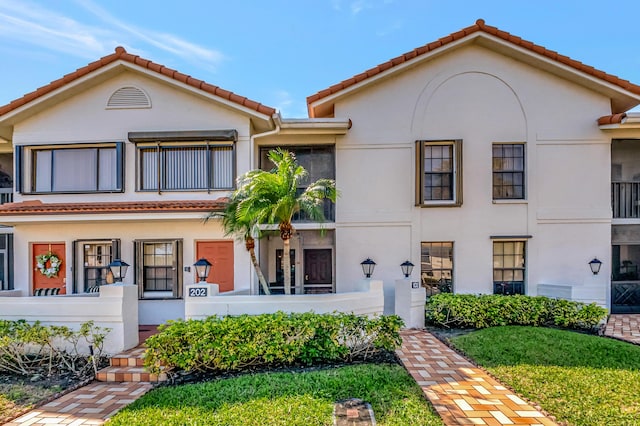 mediterranean / spanish house with stucco siding, a balcony, and a tiled roof