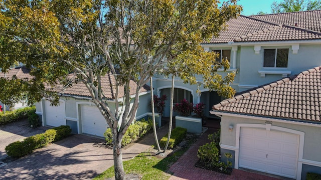 mediterranean / spanish-style house with stucco siding, decorative driveway, an attached garage, and a tiled roof