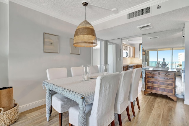 dining area with visible vents, baseboards, crown molding, a textured ceiling, and light wood-style floors