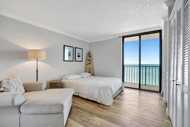 100 Ocean Trail Way Unit 1101, Jupiter, FL 33477 - bedroom with a textured ceiling, access to exterior, ornamental molding, light wood-style flooring, and a wall of windows