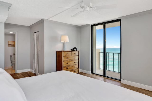 bedroom with wood finished floors, baseboards, access to outside, ornamental molding, and a wall of windows