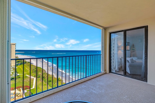 balcony featuring a view of the beach and a water view