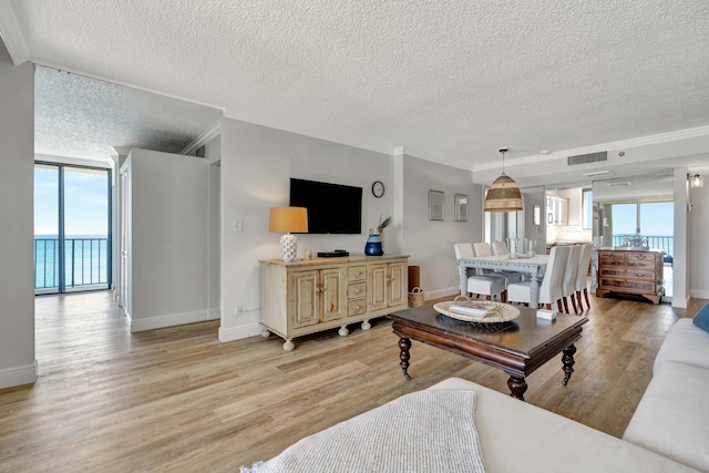 living area featuring light wood-type flooring, baseboards, visible vents, and ornamental molding