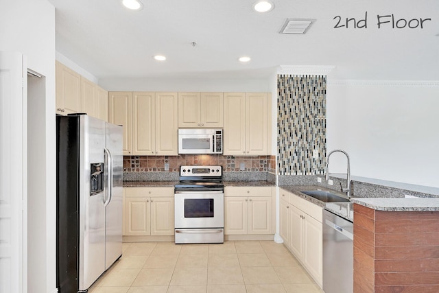 kitchen with visible vents, a peninsula, a sink, decorative backsplash, and appliances with stainless steel finishes