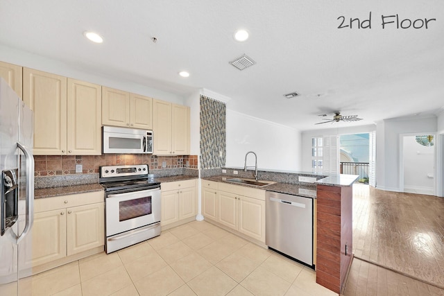 kitchen with visible vents, a peninsula, a sink, appliances with stainless steel finishes, and tasteful backsplash